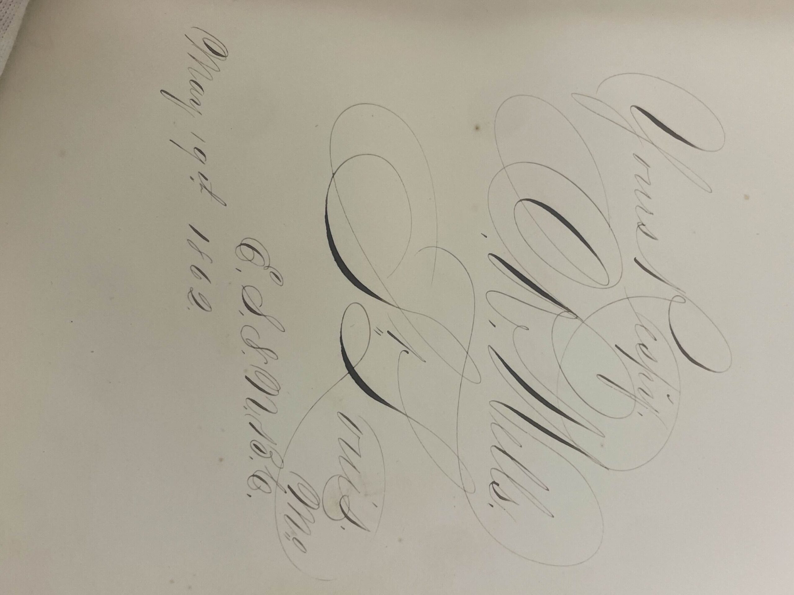 a brilliantly penned signature. a gloved hand appears on the bottom of the page.