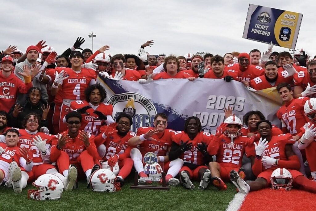 SUNY Cortland's Red Dragon football players clustered in front of a 2025 banner