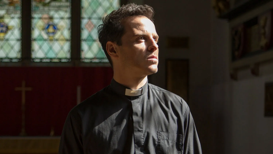 The Priest is in a church by himself. His face is looking upwards off into the distance and the light is shining directly onto his face.