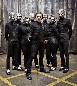 The fifth, most recent frontman, Papa V Perpetua, stands tall. His eight Nameless Ghouls stand behind him, shrouded in smoke.