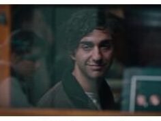 Peter stares at his reflection in a glass cabinet, where his mirrored image smiles eerily back at him while his real face remains still.